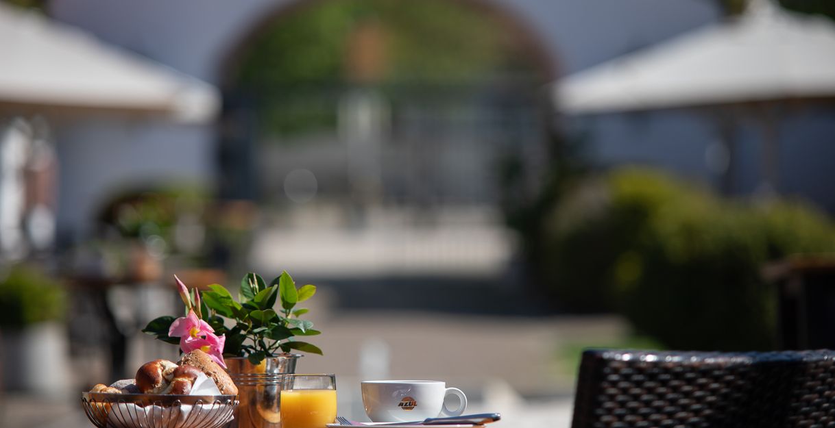 gedeckter Frühstückstisch im Innenhof mit Blick zum qweißen Eingangstor des Hotel Schloss Reinach